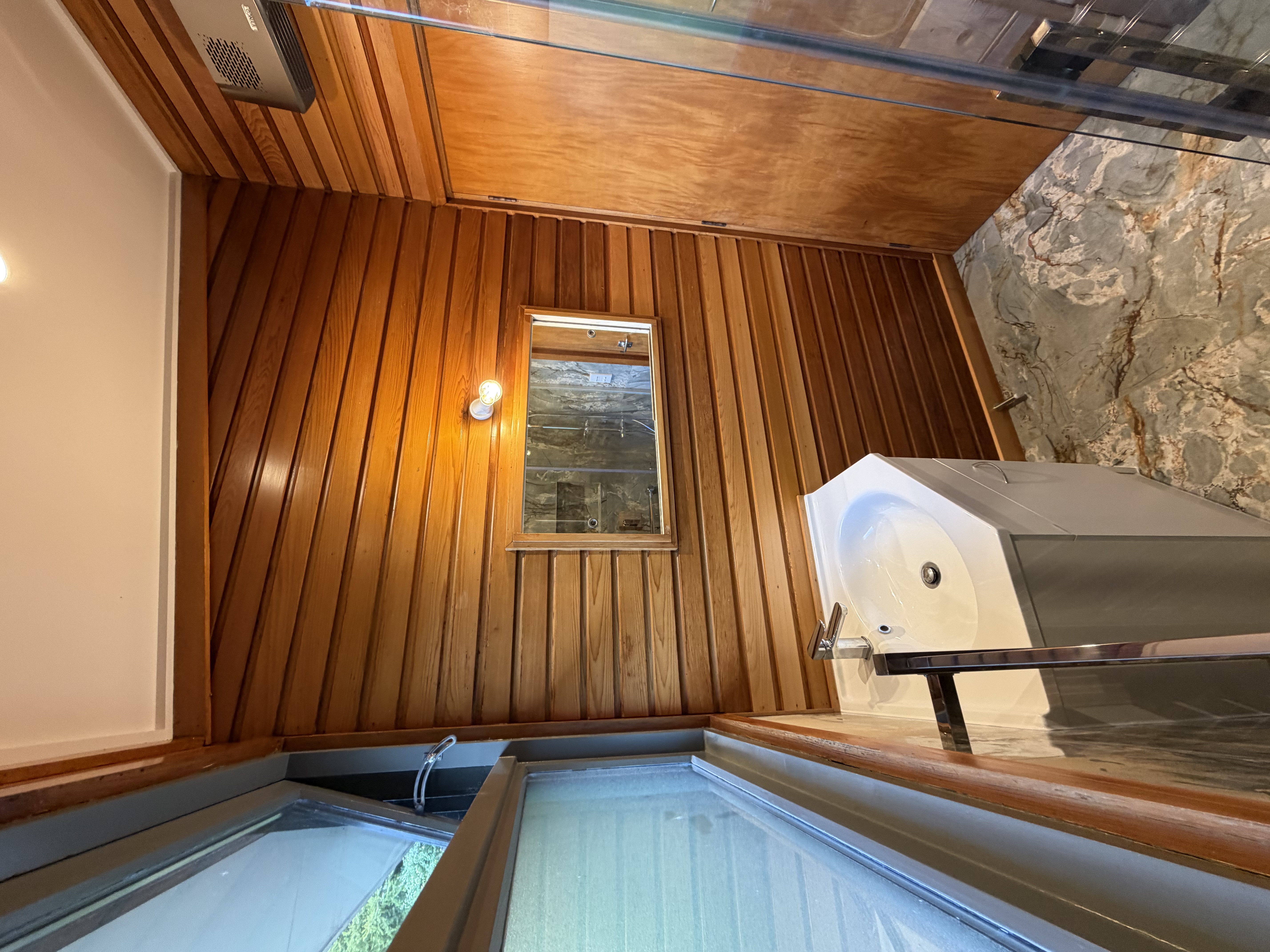 Cedar-lined bathroom with spa bath and timber panelling by Toomey Building, Dunedin